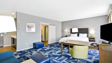 Una habitación de hotel con cama, escritorio, silla y televisor.