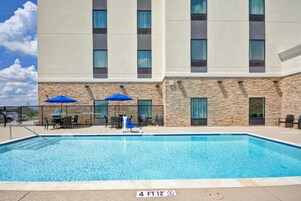 Una piscina al aire libre, sillones reclinables de piscina