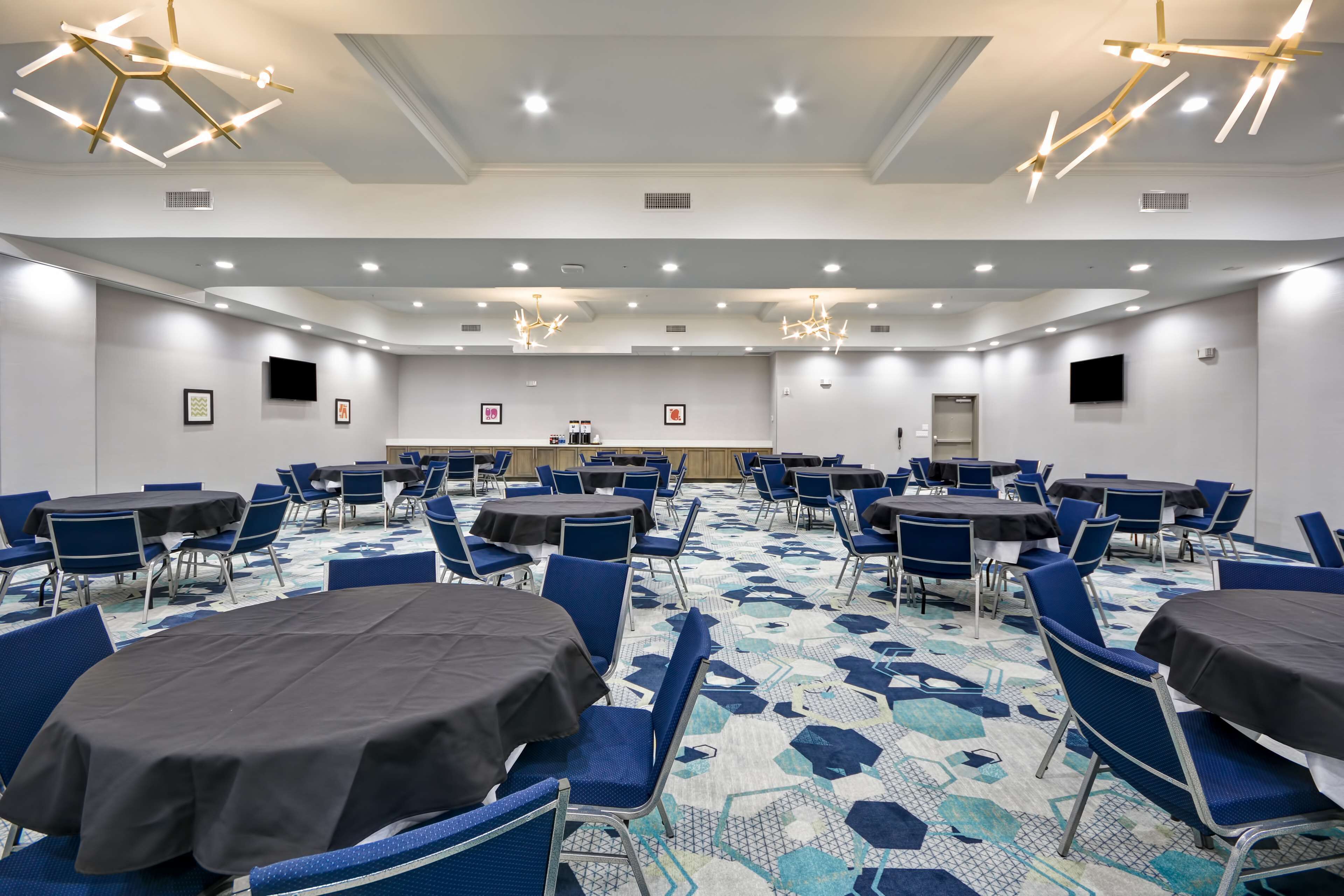 A conference room with round tables, blue chairs, and a patterned carpet.