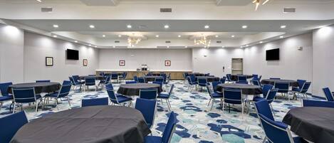 A conference room with round tables, blue chairs, and a patterned carpet.