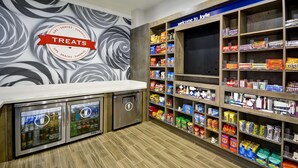 A snack and treat display area with a 'Treats' sign, a 'Welcome to Kyle' sign, and a variety of snacks and beverages. - Hampton Inn Kyle (Kyle)
