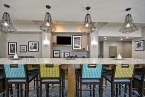 A modern kitchen with a central island, bar stools, pendant lighting, and framed artwork on the walls.