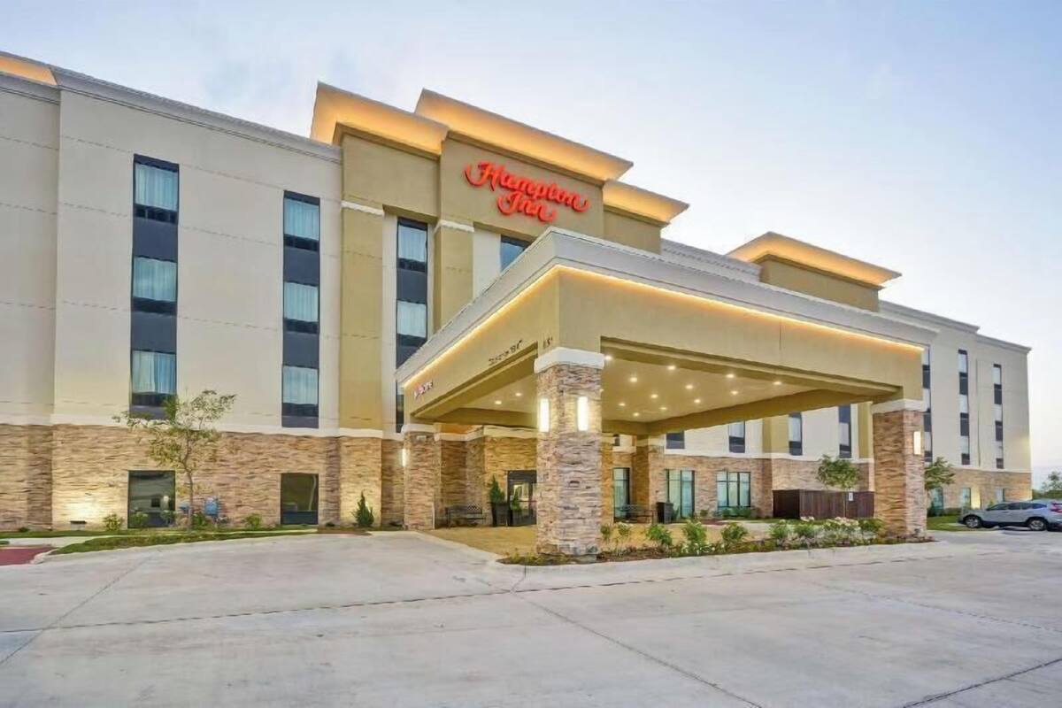 A Hampton Inn hotel with a covered entrance, stone facade, and multiple windows.