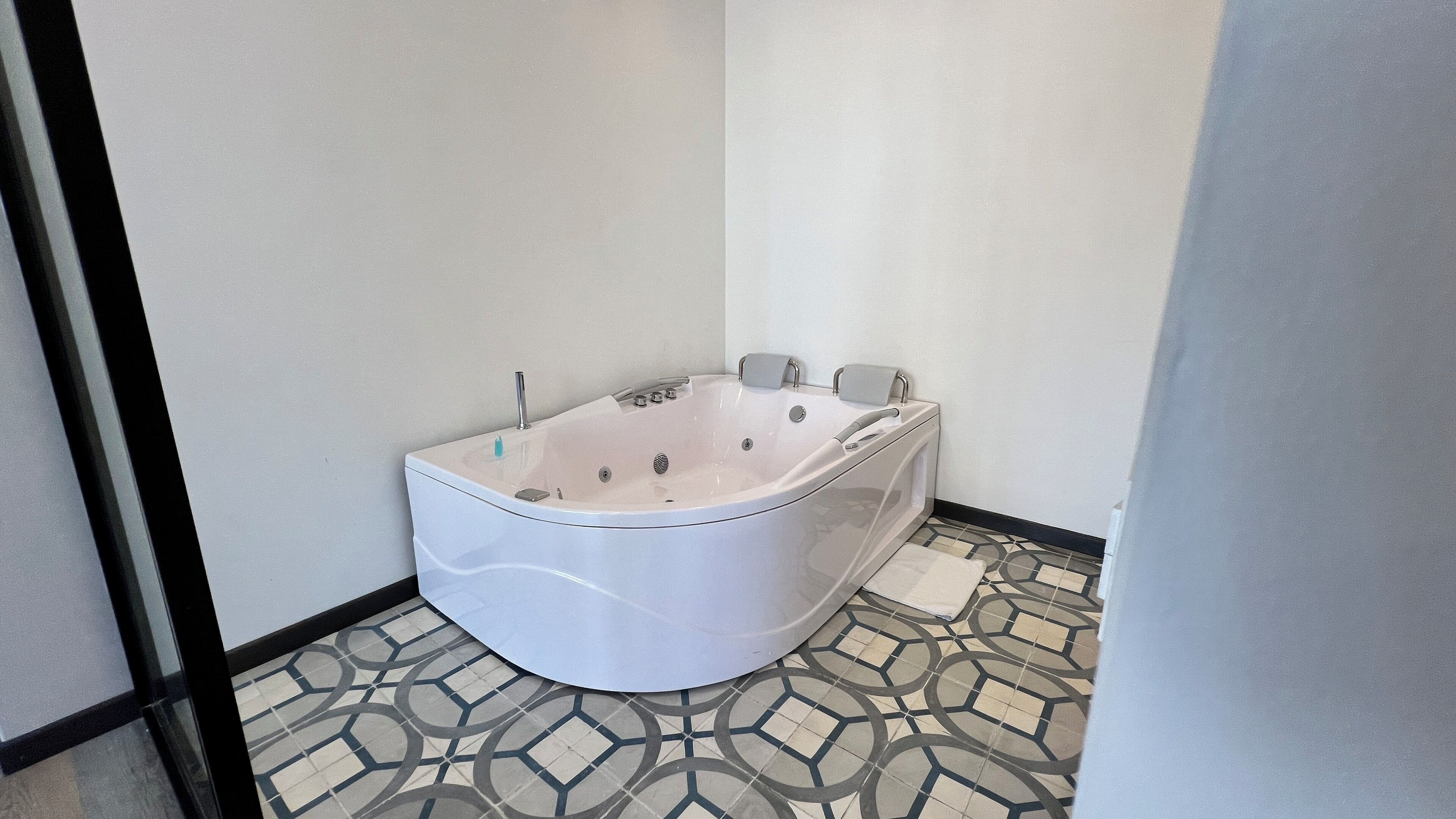 Un baño moderno con una bañera independiente, un inodoro y un piso con diseño.