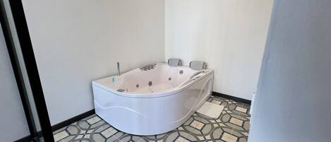 Un baño moderno con una bañera independiente, un inodoro y un piso con diseño.