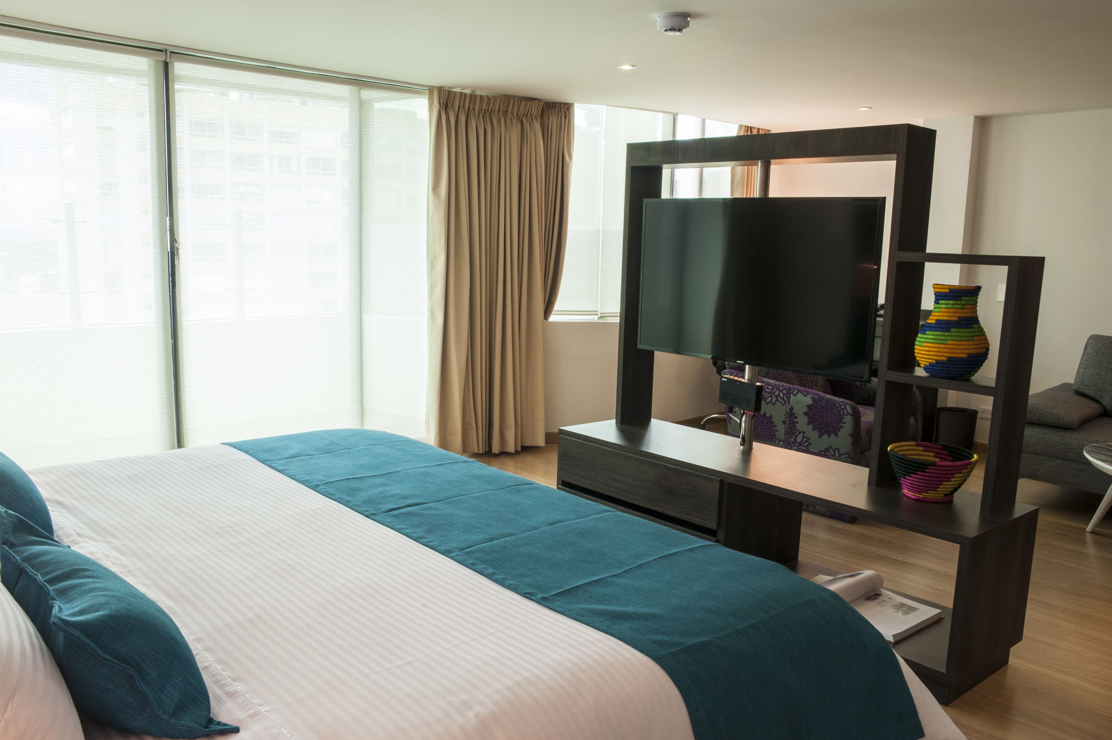 Une chambre d’hôtel avec un grand lit, un téléviseur à écran plat, un bureau avec un ordinateur et une fenêtre avec des rideaux.