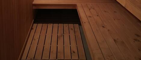 Una sauna de madera con bancos y piso inclinado.
