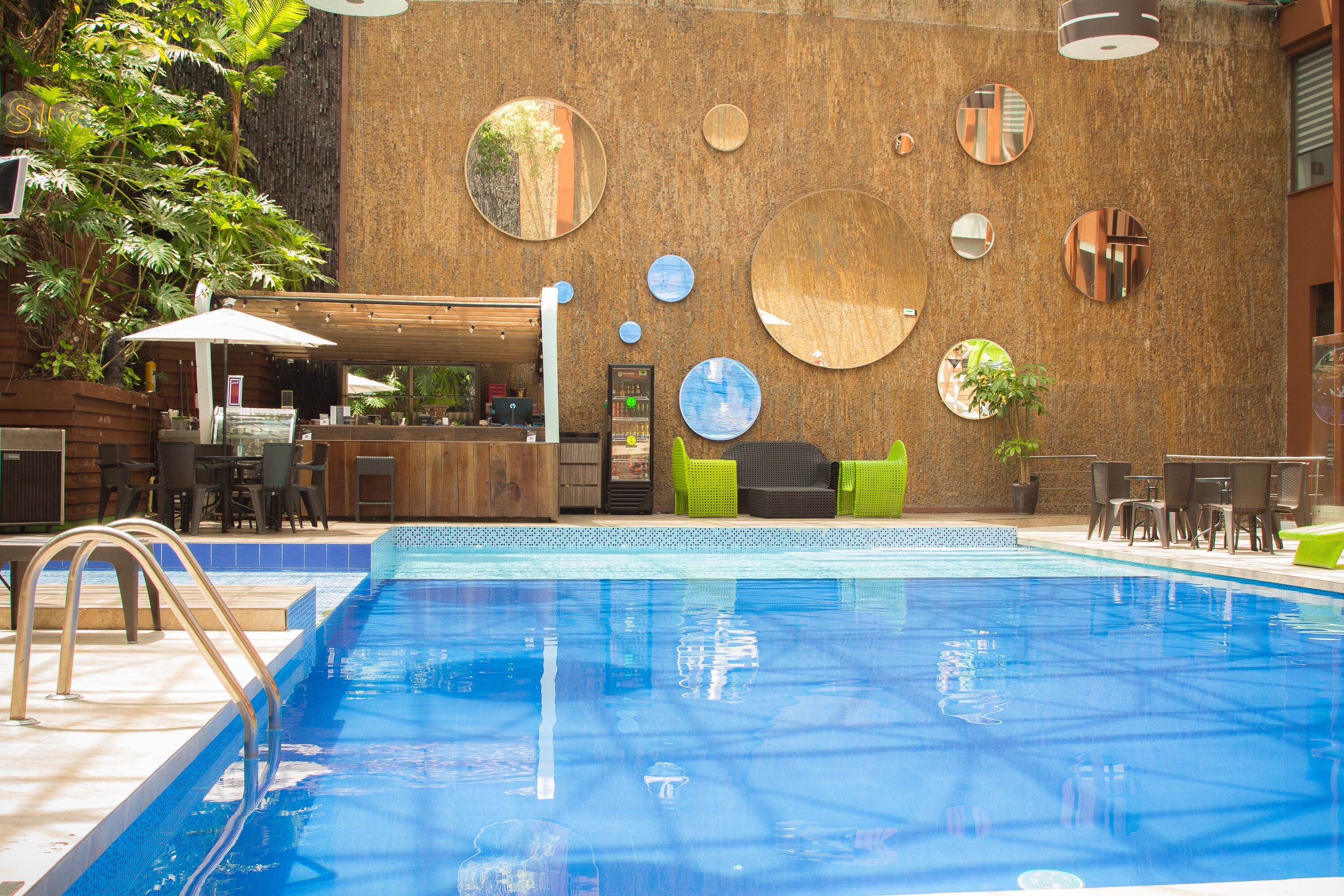 Una piscina con cubierta de madera, zona de estar y bar.