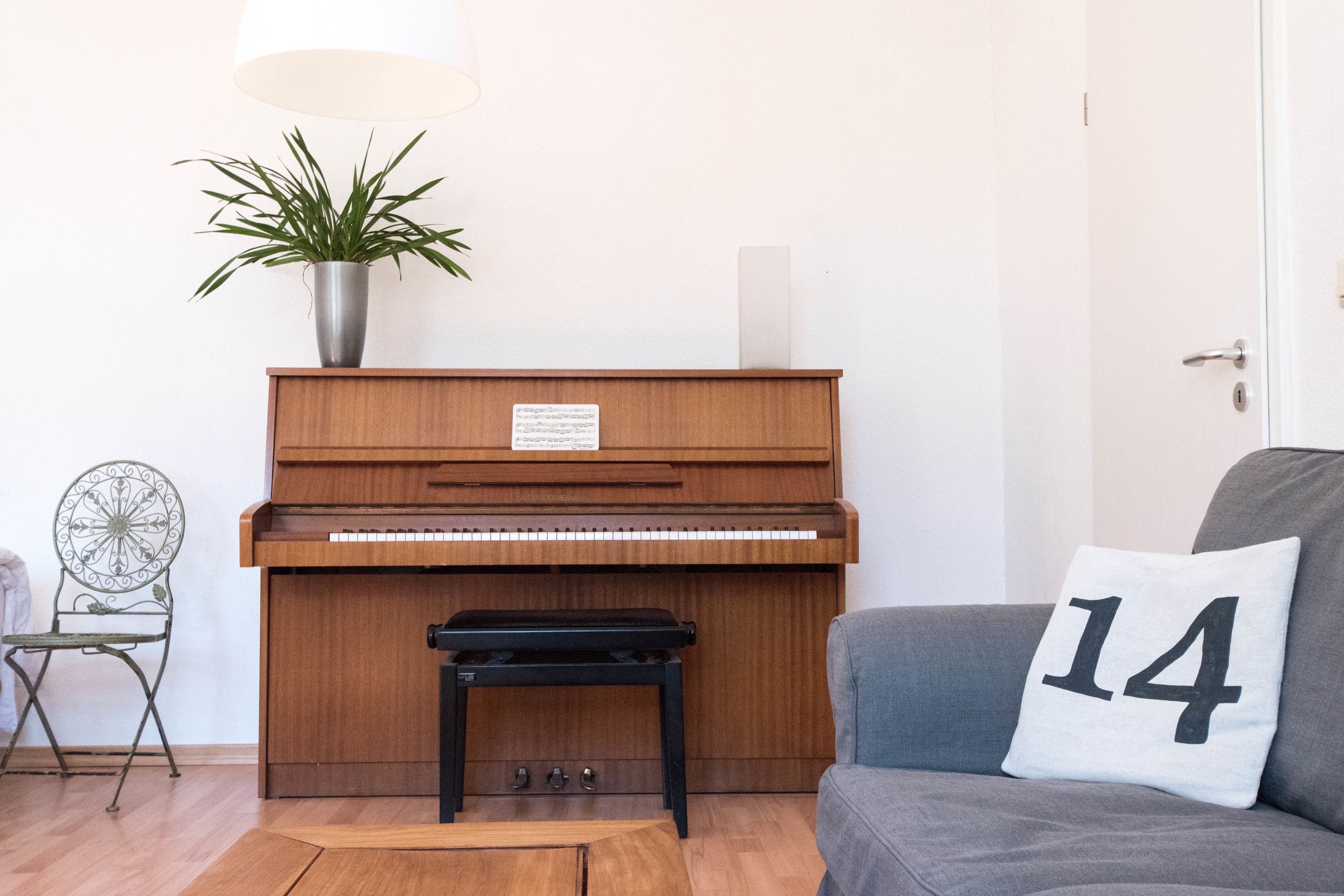 A piano, a plant, a chair, and a cushion with the number 14.
