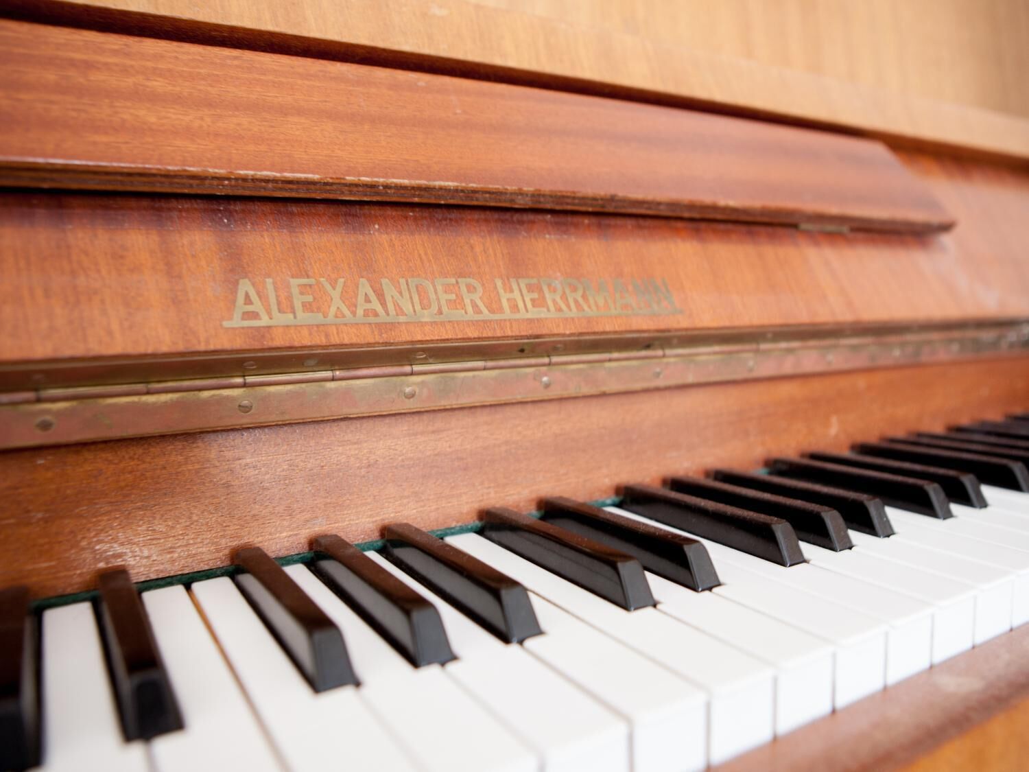 Nahaufnahme eines Klaviers mit dem Namen "ALEXANDER HERRMANN", der ins Holz eingraviert ist.