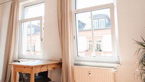 A room with two windows, a wooden desk, and a radiator. - Peters Wohnung (Weimar)