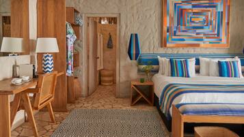 A bedroom with a bed, bedside tables, a chair, a desk, and a wall with a geometric painting.