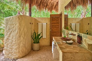 A bathroom with a stone sink, wooden door, and a potted plant. - Blue Apple Beach  (Cartagena)
