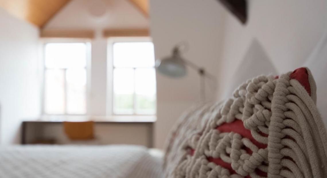 A cozy bedroom with a bed, a window, and a lamp.