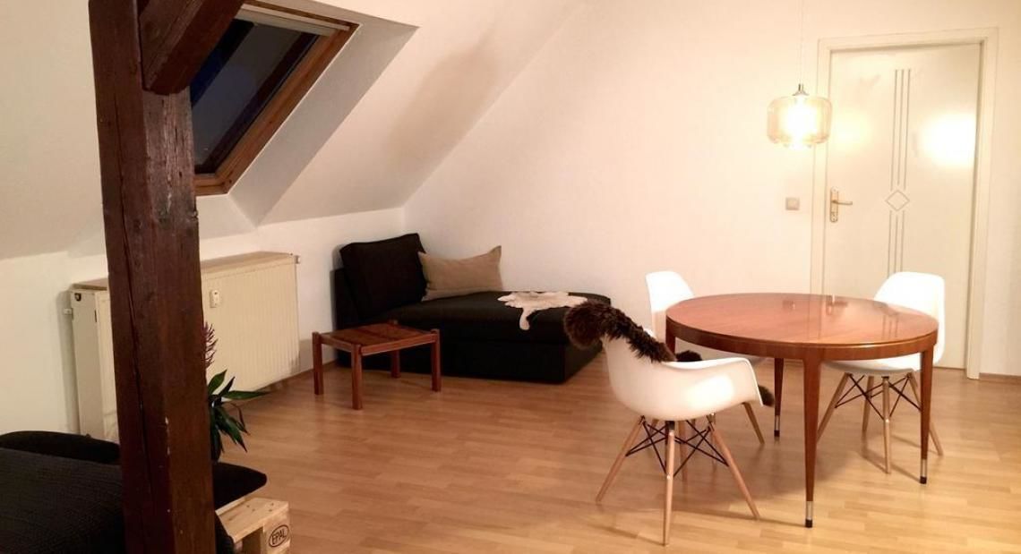 A cozy loft apartment with a dining area, a sofa, and a small table.