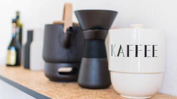 Una encimera de cocina con una cafetera, un hervidor y una taza de café que dice "KAFFEE".