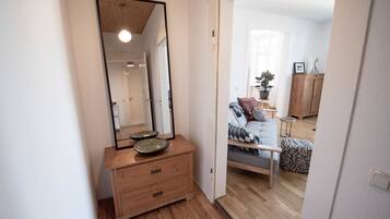 Una habitación con tocador de madera, un espejo grande y una cama con ropa de cama estampada.