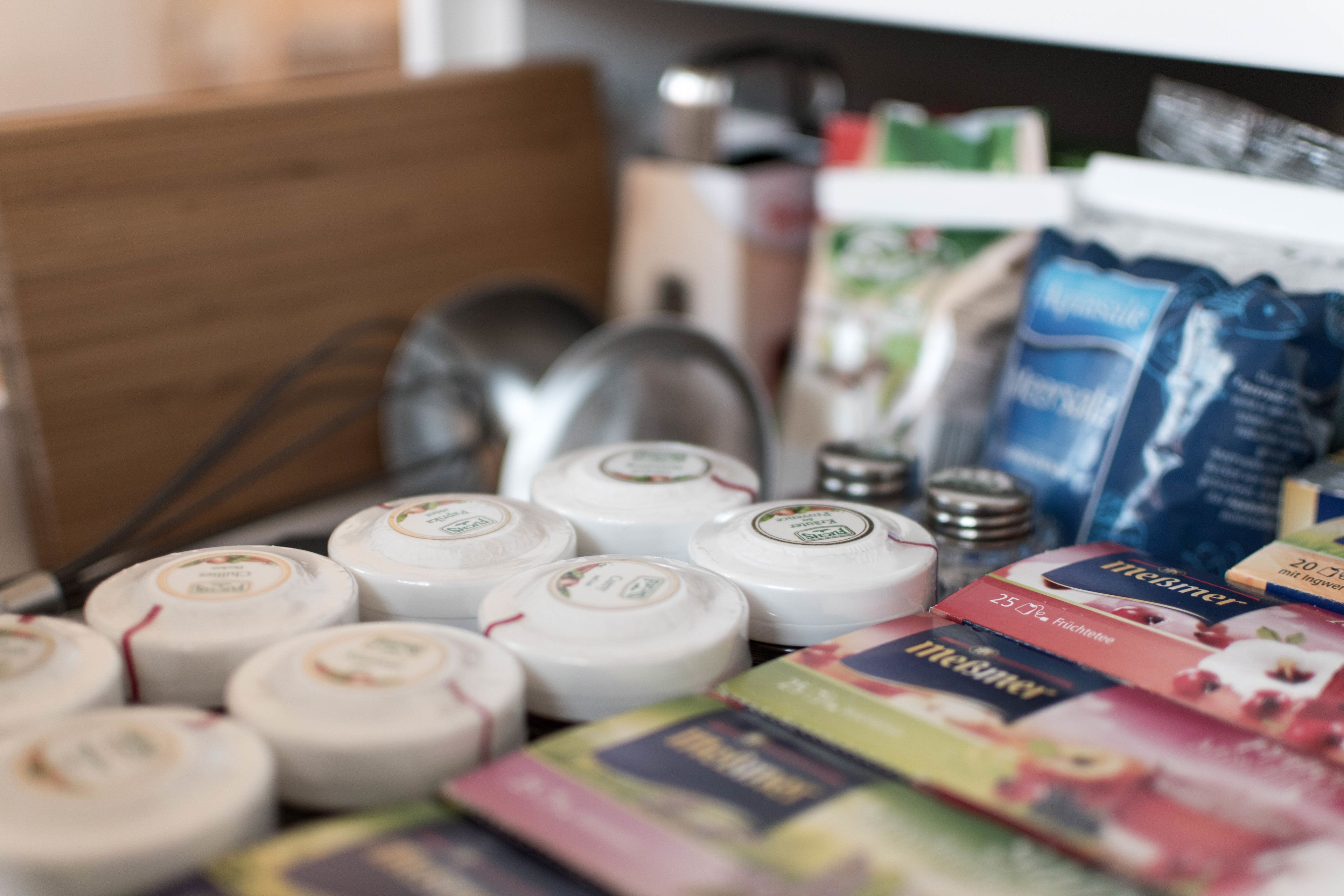 Verschiedene verpackte Lebensmittel, darunter Käse und Snacks, sind auf einer Oberfläche angeordnet.