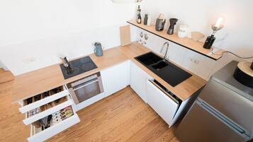 Une cuisine moderne dotée d’un plan de travail en bois, d’appareils électroménagers en acier inoxydable et d’un four encastré.