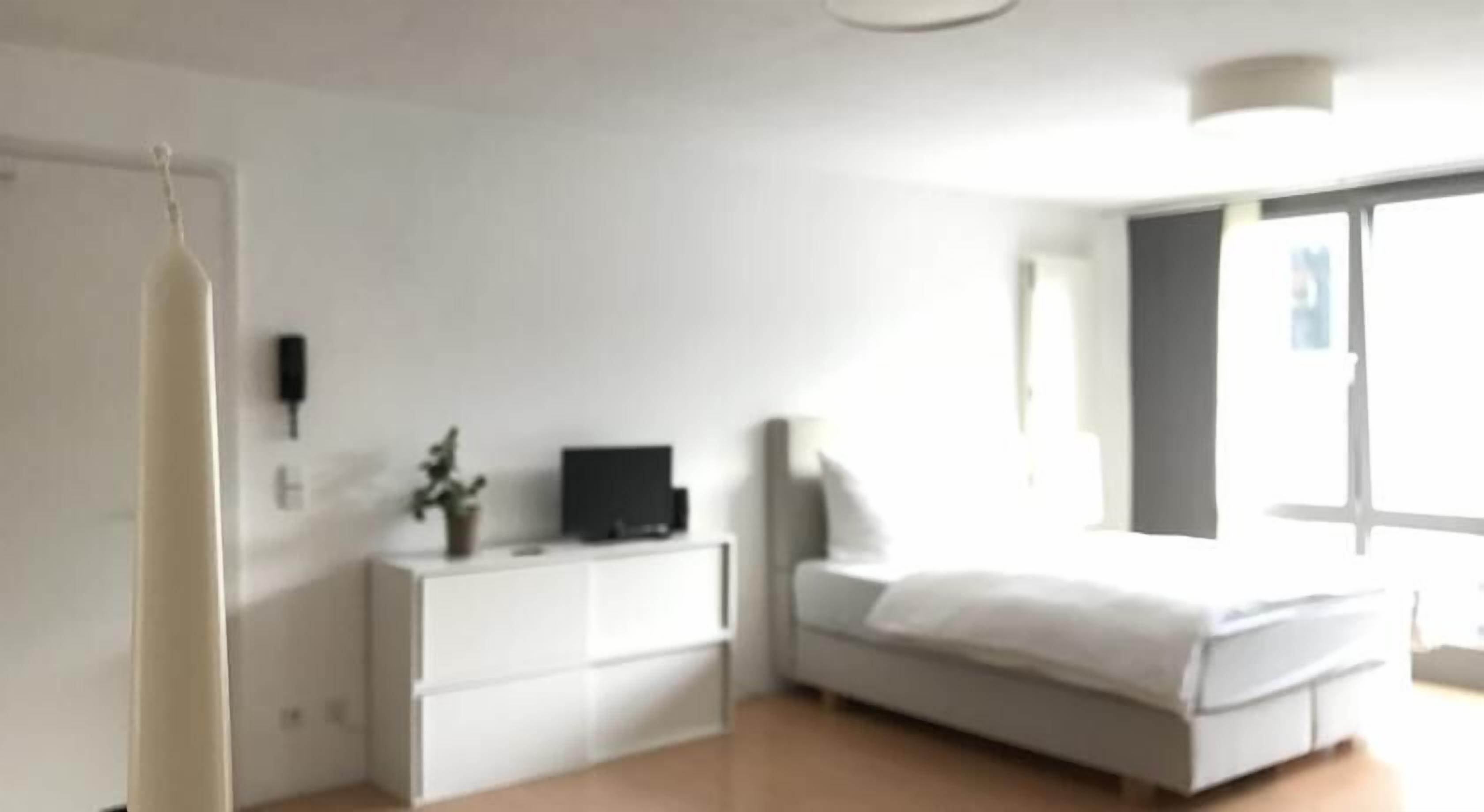 Un dormitorio con una cama, un aparador, un televisor y una ventana.