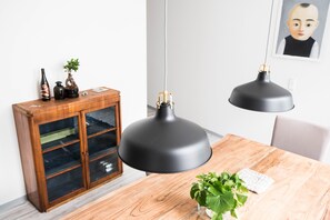 A dining area with a wooden table, black pendant lamps, a cabinet with glass doors, and a framed picture on the wall. - Altstadt Suite (Weimar)