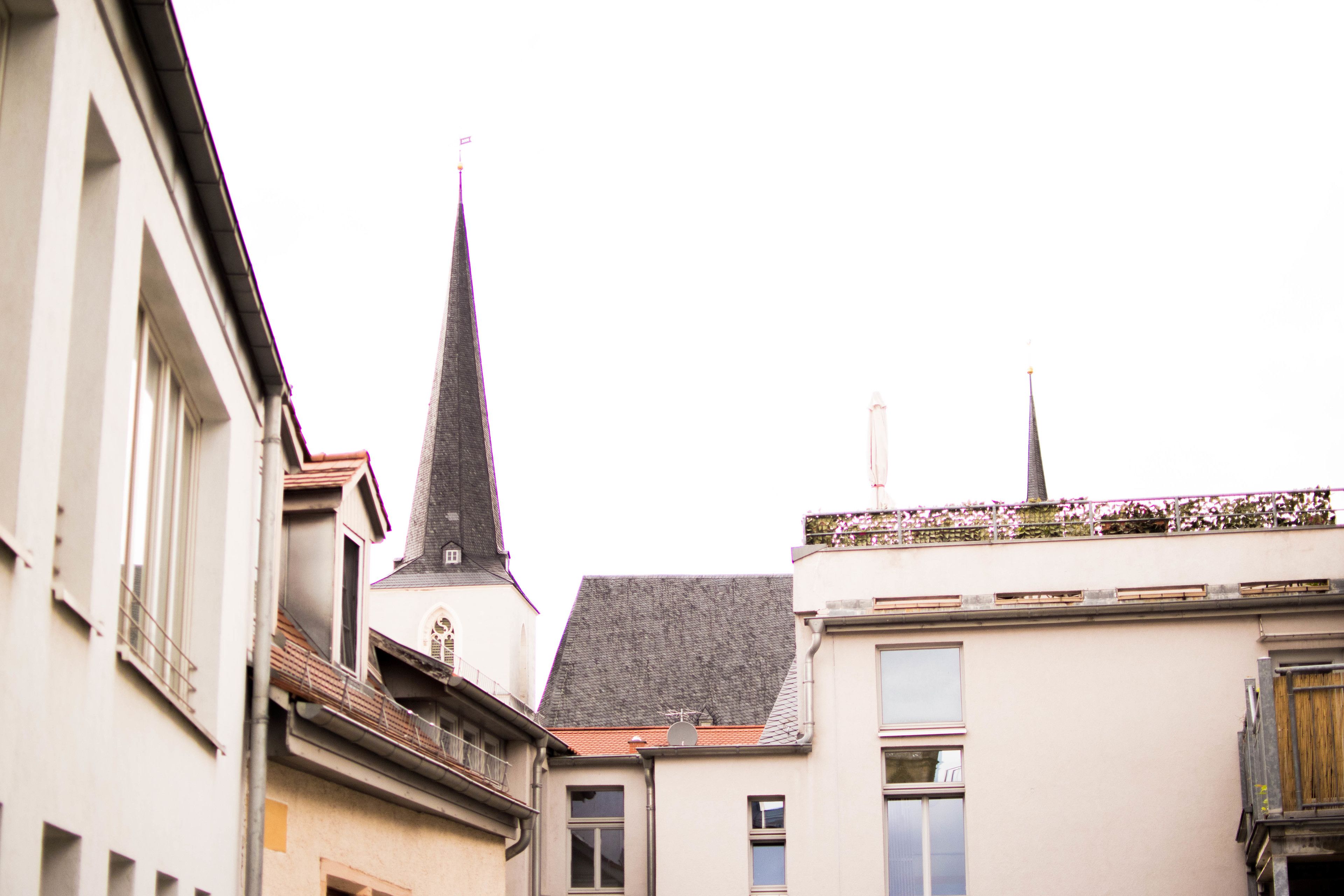 Eine enge Straße mit Gebäuden, darunter eine Kirche mit einem hohen Kirchturm und ein Gebäude mit einem geneigten Dach.