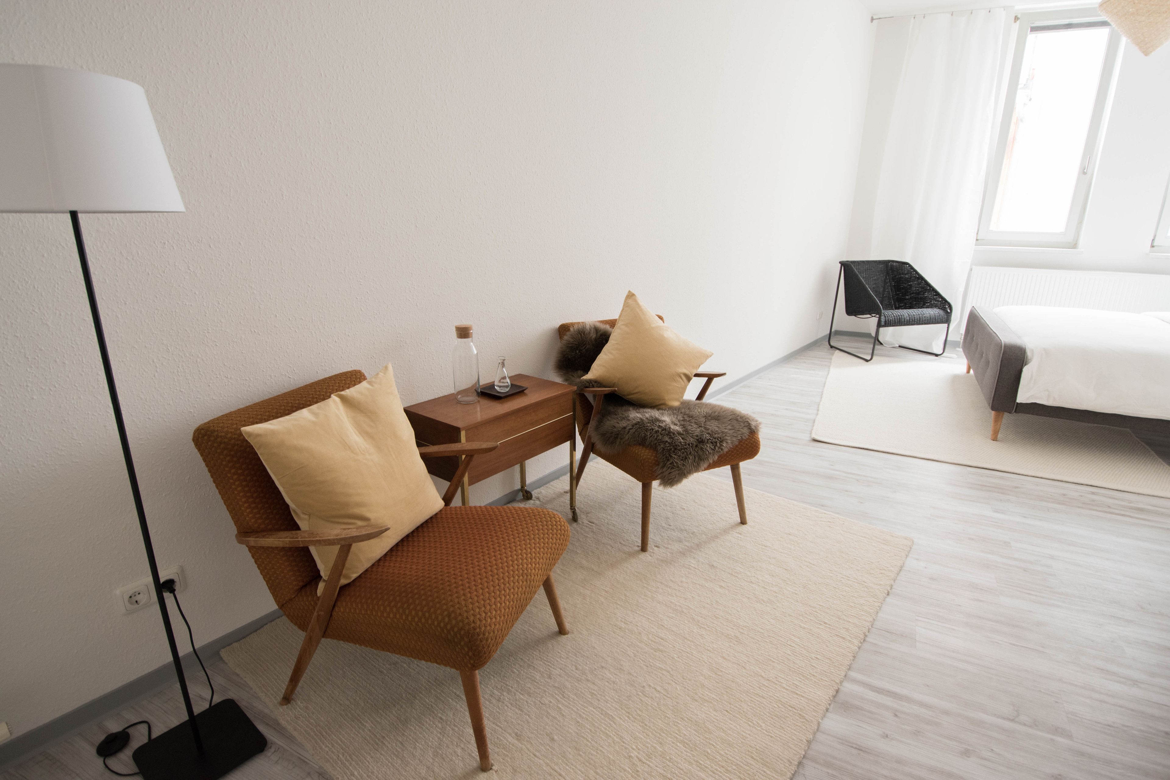 Une chambre d’hôtel moderne comprenant un lit, un bureau avec une lampe, une chaise et une petite table.