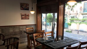 A restaurant interior with wooden tables and chairs, a tiled floor, and a view of the street outside. - Hostal Mitad del Mundo (Quito)