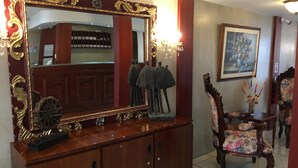 A wooden console with a large mirror and a chandelier. - Hostal Mitad del Mundo (Quito)