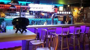 A bar with a counter, stools, and a neon sign. - Hostal Mitad del Mundo (Quito)
