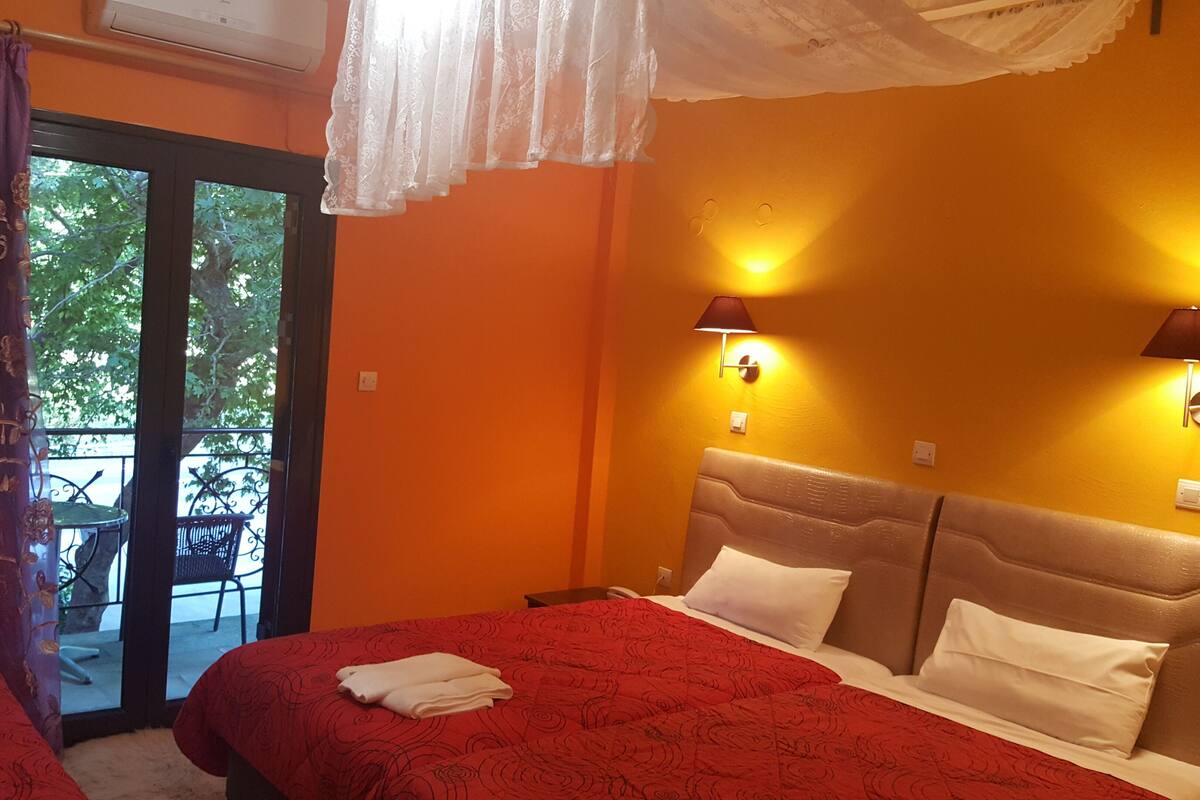 Une chambre d’hôtel avec deux lits, un balcon avec une chaise et deux lampes fixées au mur.