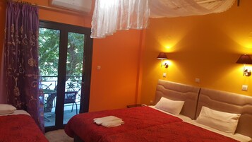 Habitación de hotel con dos camas, un balcón con una silla y dos lámparas fijadas a la pared.