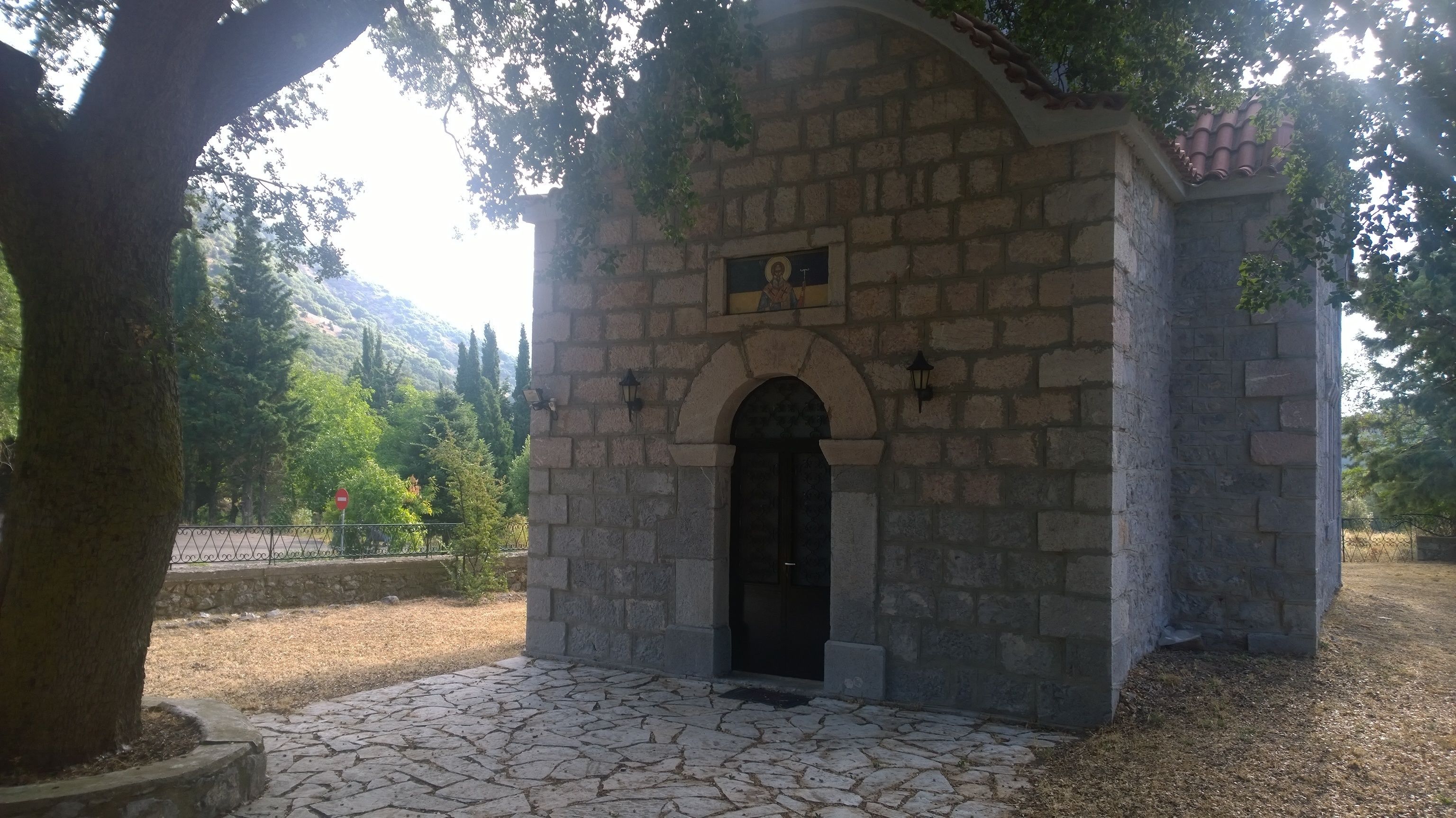A stone building with an arched entrance, a small balcony, and a door.
