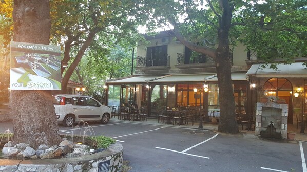 A restaurant with outdoor seating, a parking area, and a signboard advertising a hotel. - Hani Zemenou (Distomo-Arachova-Antikyra)