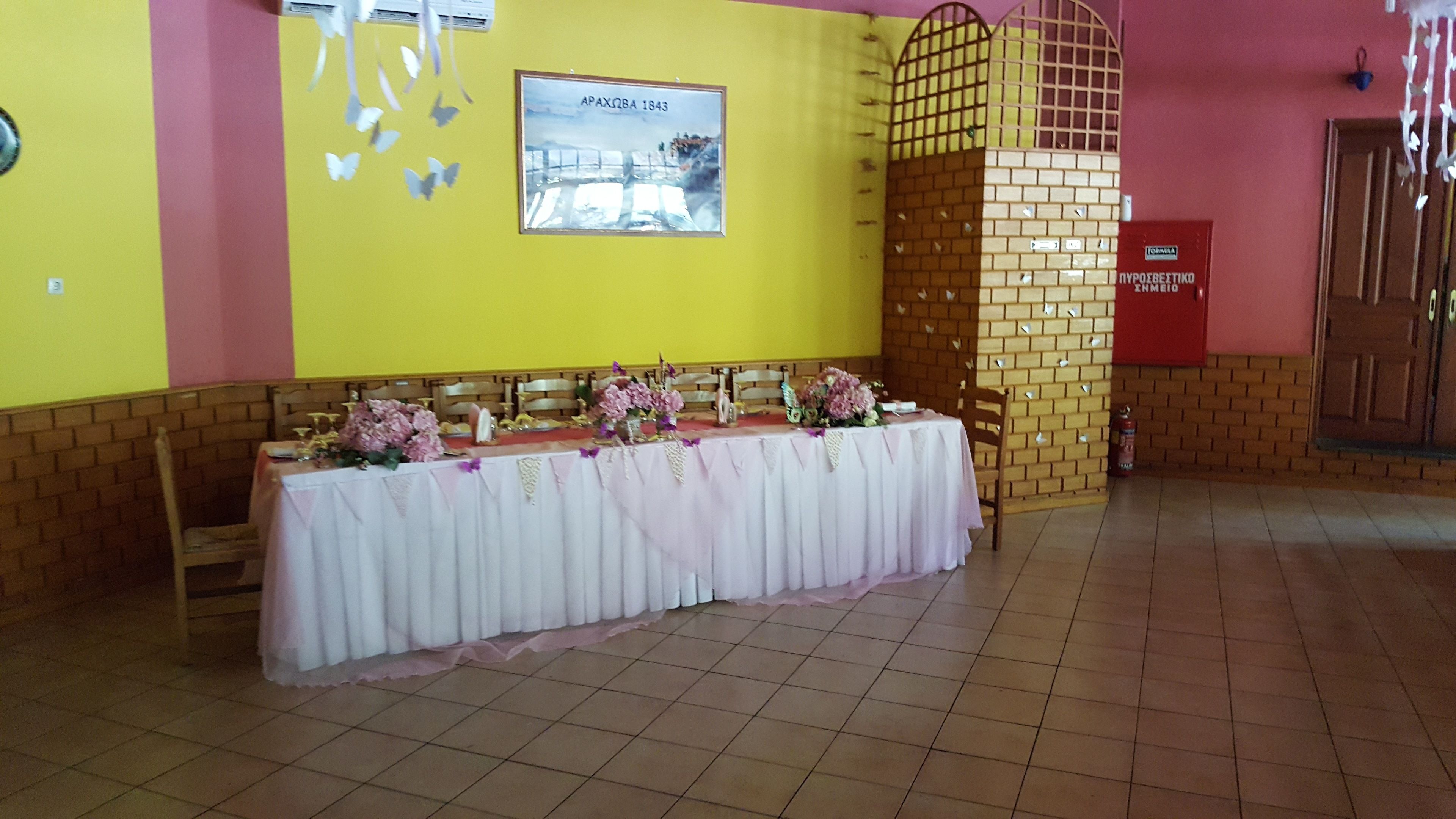 A banquet hall with a long table covered in a white tablecloth, flanked by chairs.