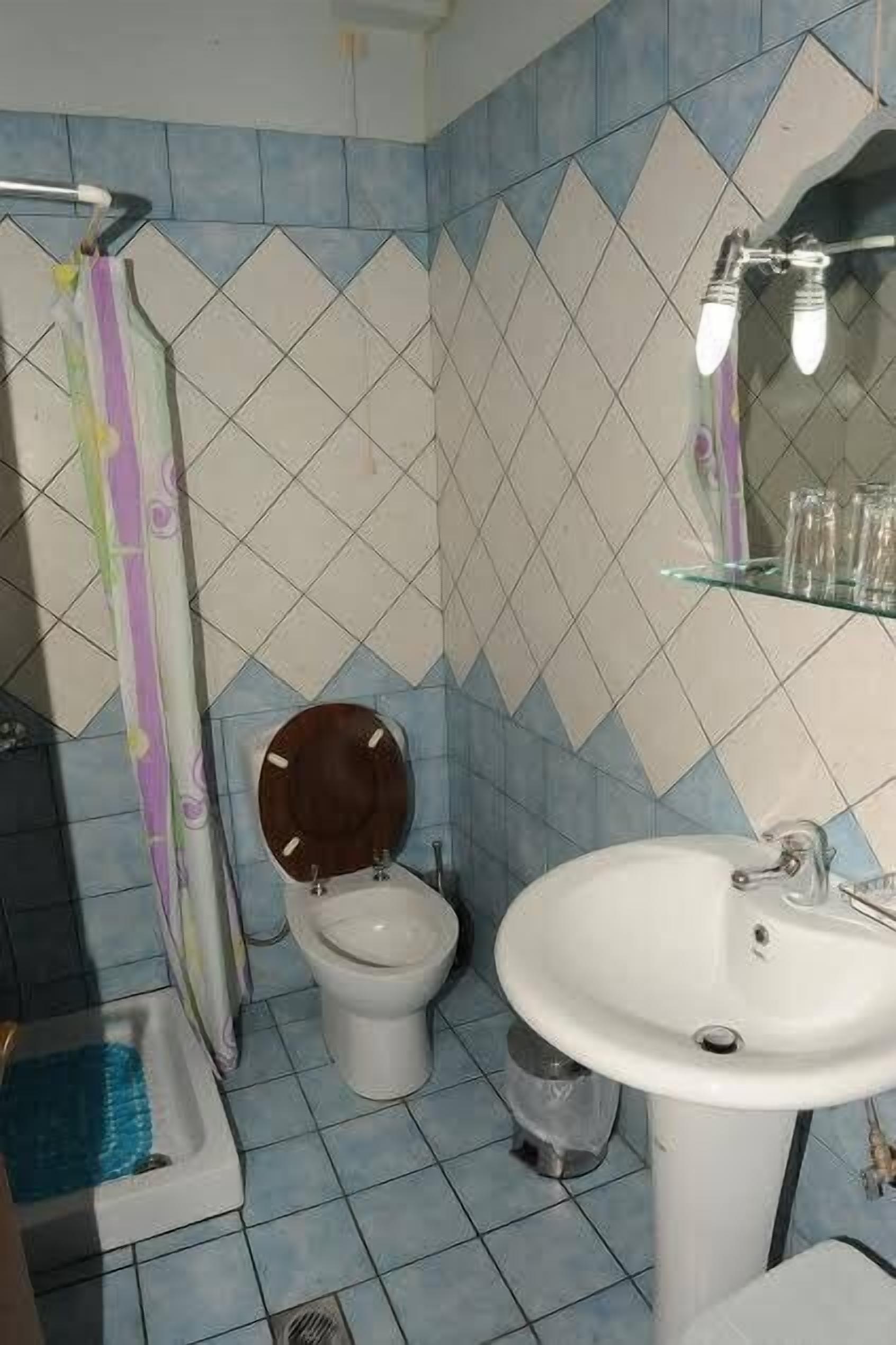 A bathroom with a shower, toilet, sink, and a mirror.
