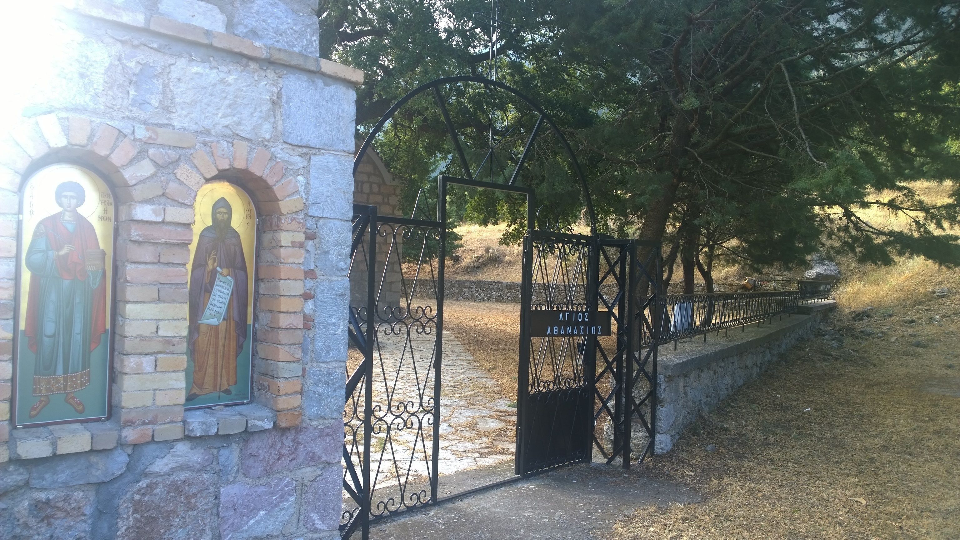 Um edifício de pedra com ícones religiosos e um portão de metal.
