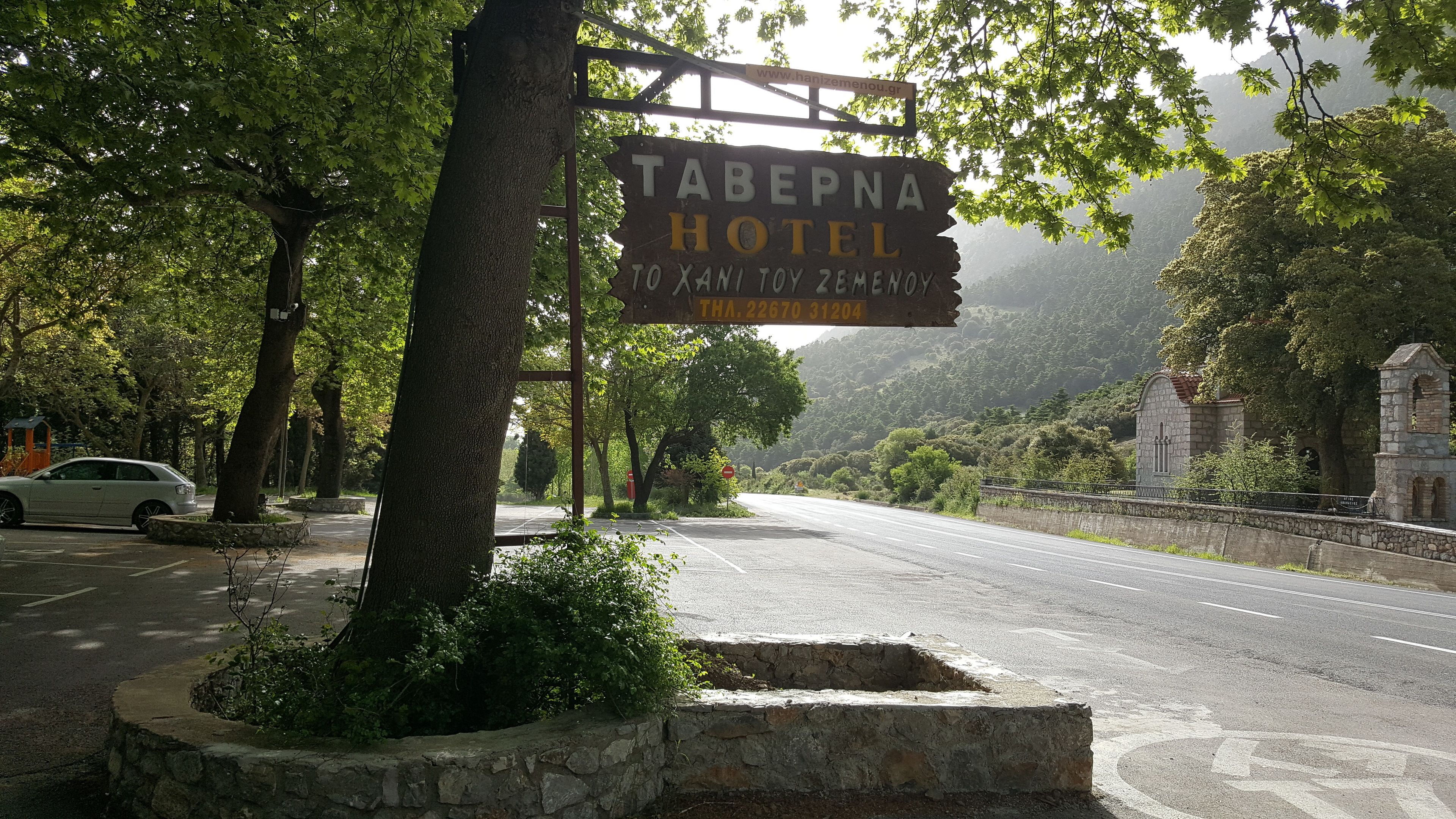 Señal del Hotel Taberna con vista a una carretera y follaje circundante.