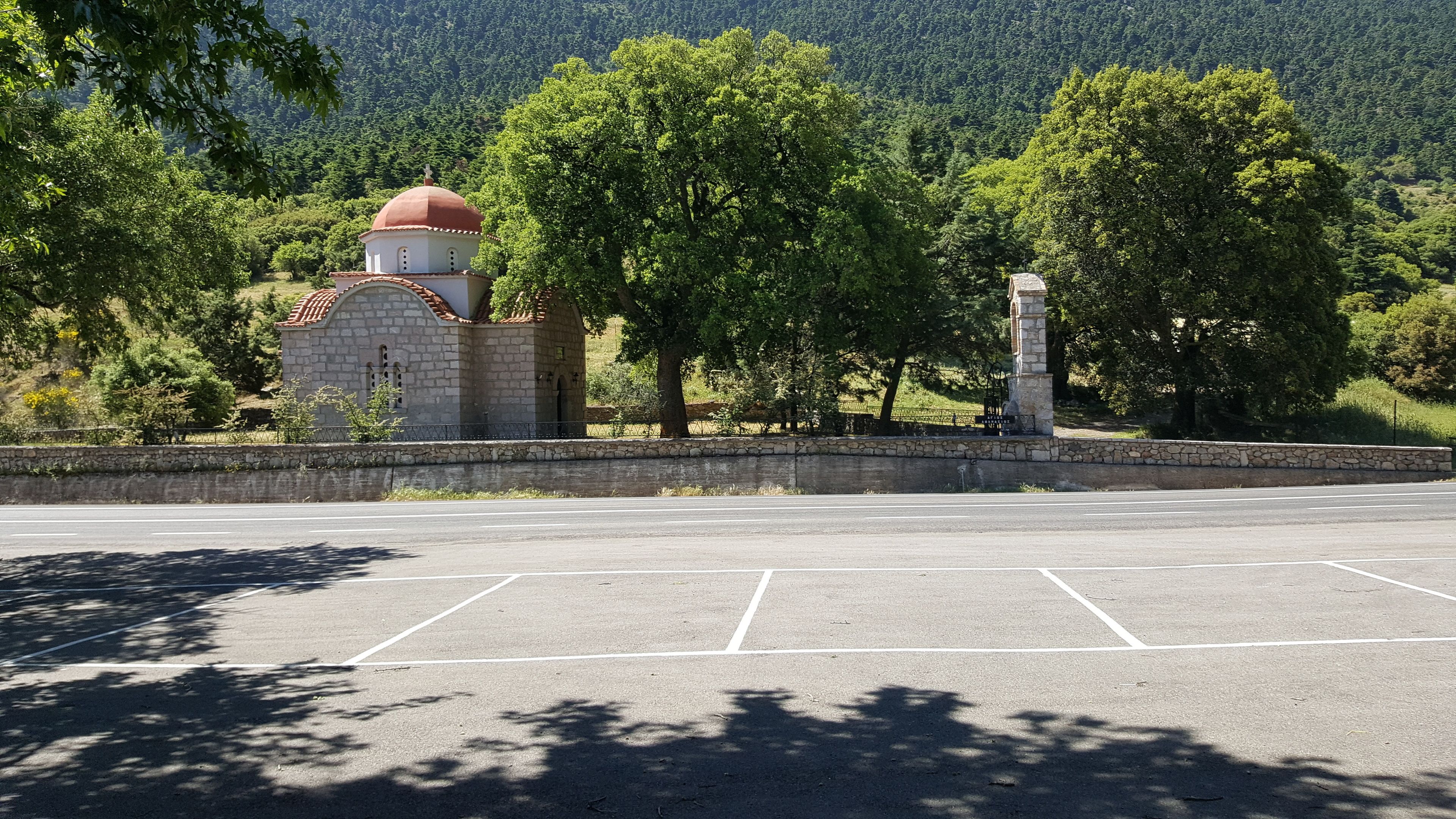 A parking lot with a stone wall and a small building with a dome.