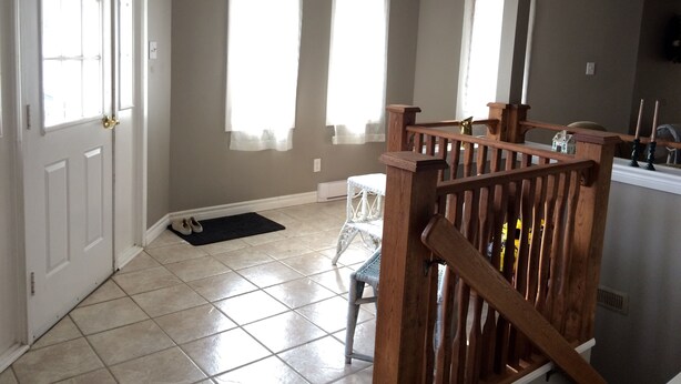 A room with a wooden staircase, a white door, and a window with a white curtain. - Inn Towne Cottage (Bancroft)