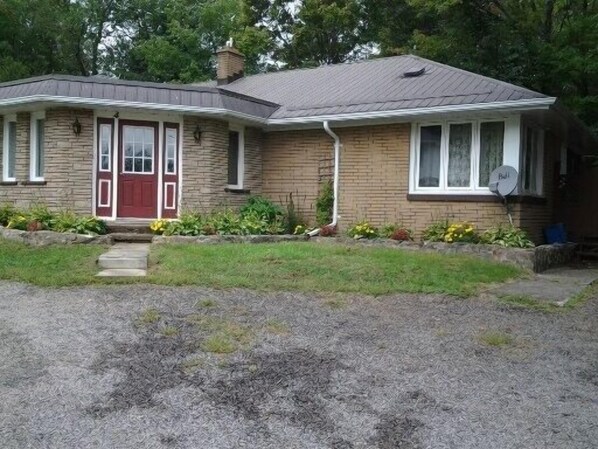 A two-story house with a red door, a satellite dish, and a small front porch.