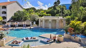A hotel with a swimming pool surrounded by palm trees and lounge areas.