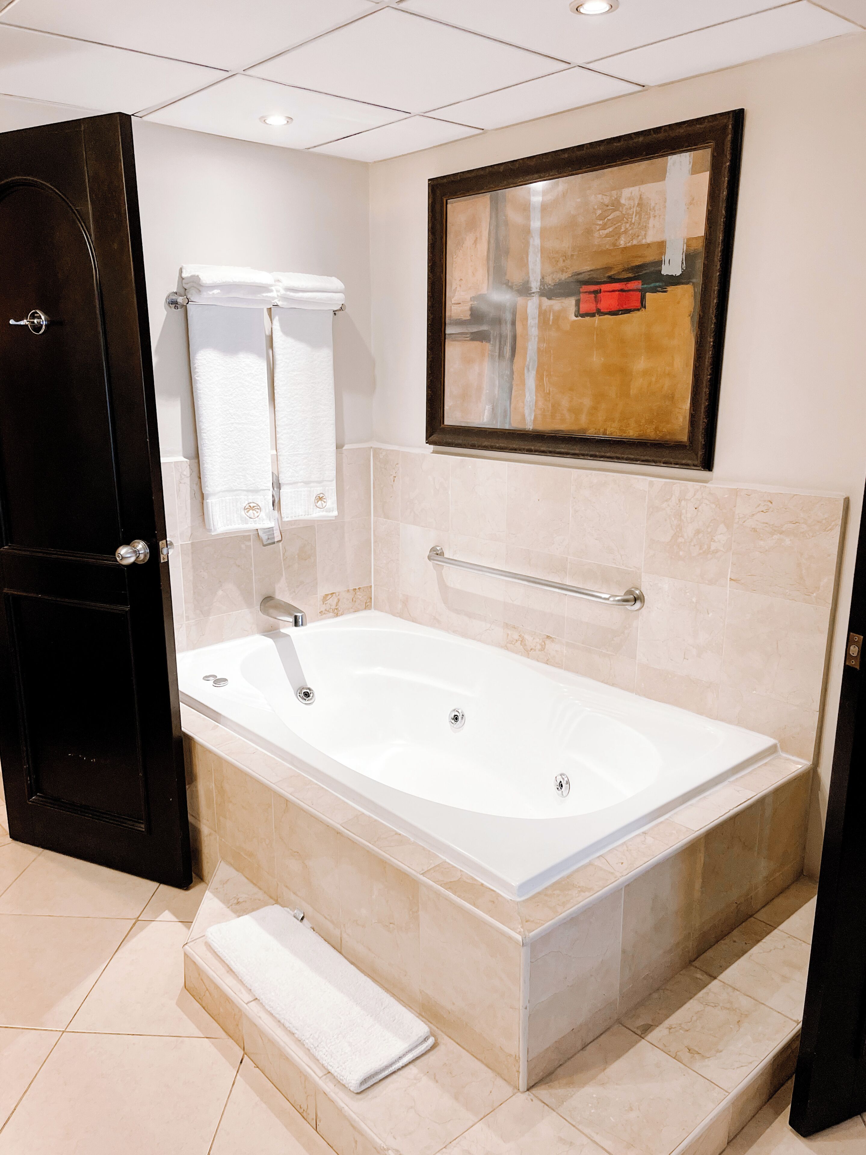 Un bagno moderno con una vasca da bagno indipendente, un porta asciugamani e un'opera d'arte incorniciata al muro.