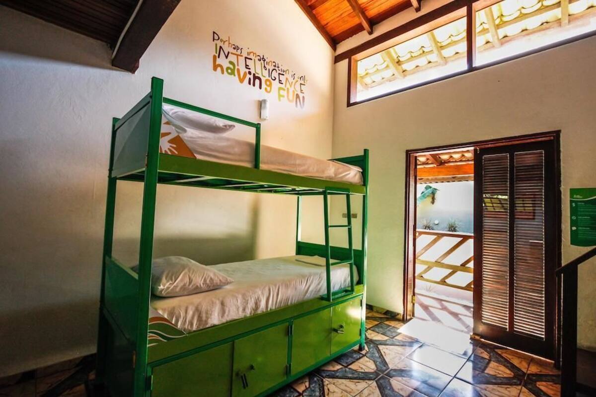 Una habitación con literas, suelo de baldosas y una pared decorada con una frase inspiradora.