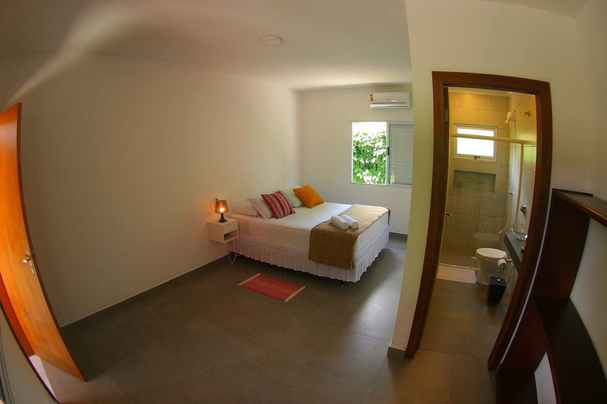 Un dormitorio con cama, mesita de noche y ventana.