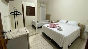 Une chambre d’hôtel comprenant un lit, une table de chevet, un porte-vêtements et un espace douche.