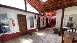 Ein überdachter Patio-Bereich mit Steinböden, Holzmöbeln und einem an der Wand befestigten Feuerlöscher.