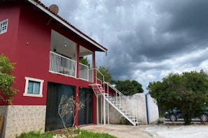 Un immeuble de deux étages avec une façade rouge, un balcon et un escalier menant à l’étage supérieur.