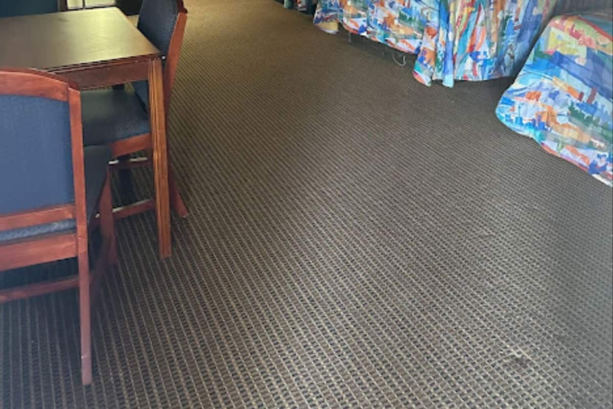 A hotel room with two beds, a desk, a chair, and a lamp.