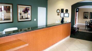 A reception area with a wooden reception desk, framed artwork on the wall, and a clock.